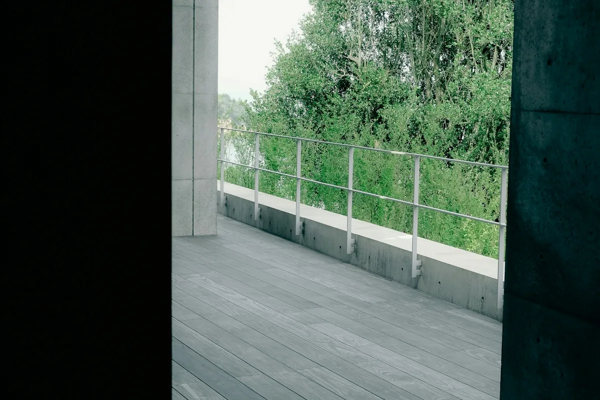 Timber decking beside a contemporary concrete building and trees